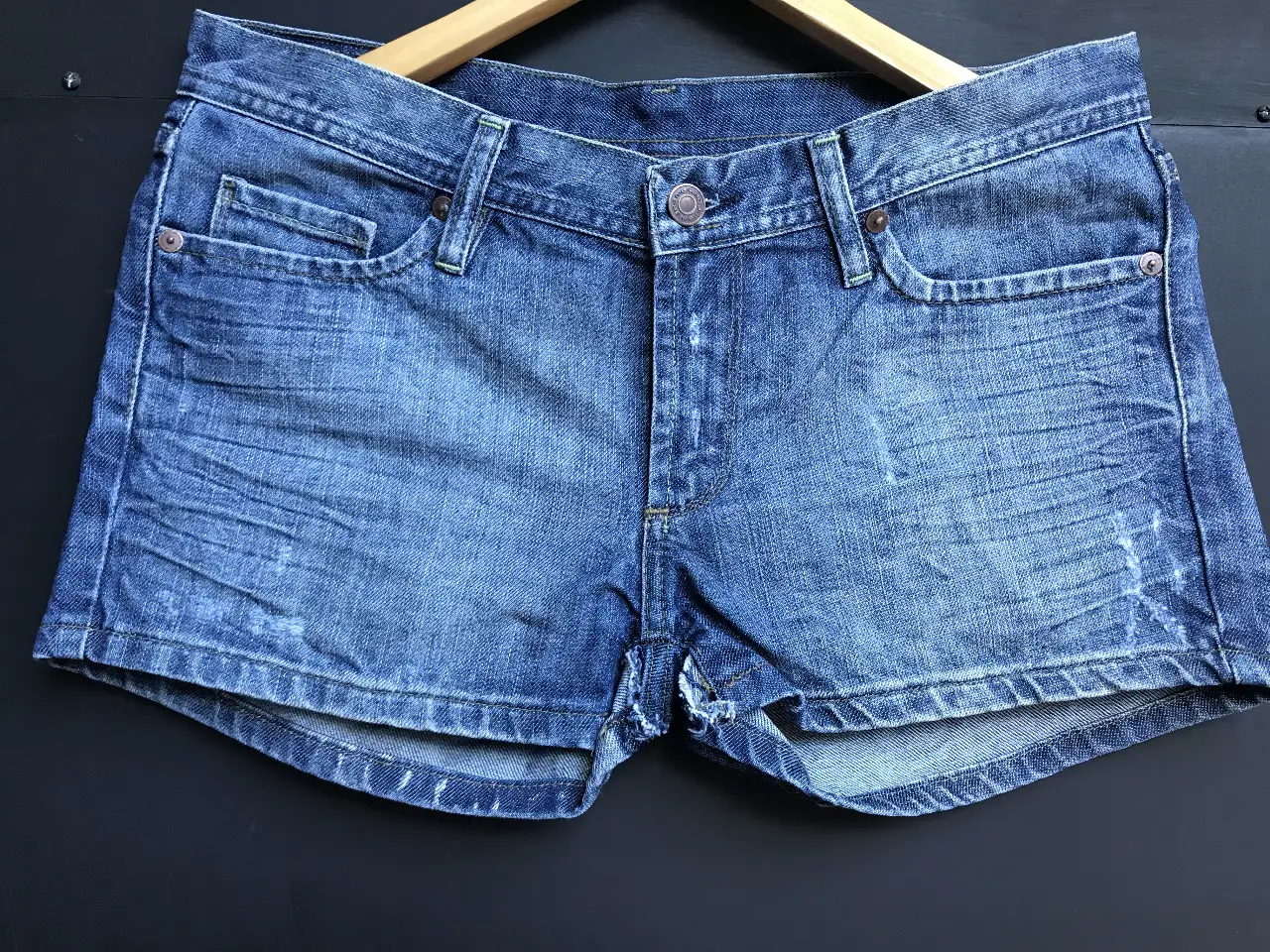 Short de jean azul Wanama con detalles desgastados y un bordado de mariposa en el bolsillo trasero. Talle 28.
