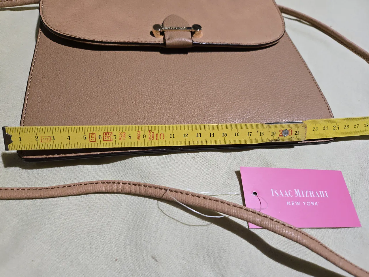 Cartera de cuero color tiza con correa larga. Posee un bolsillo interno con cierre y otro abierto. Cierre principal a presión.