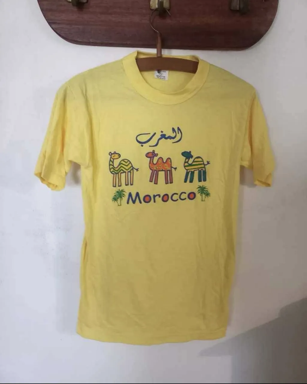 Remera amarilla con estampado de camellos y la palabra 'Morocco'. Estilo vintage.