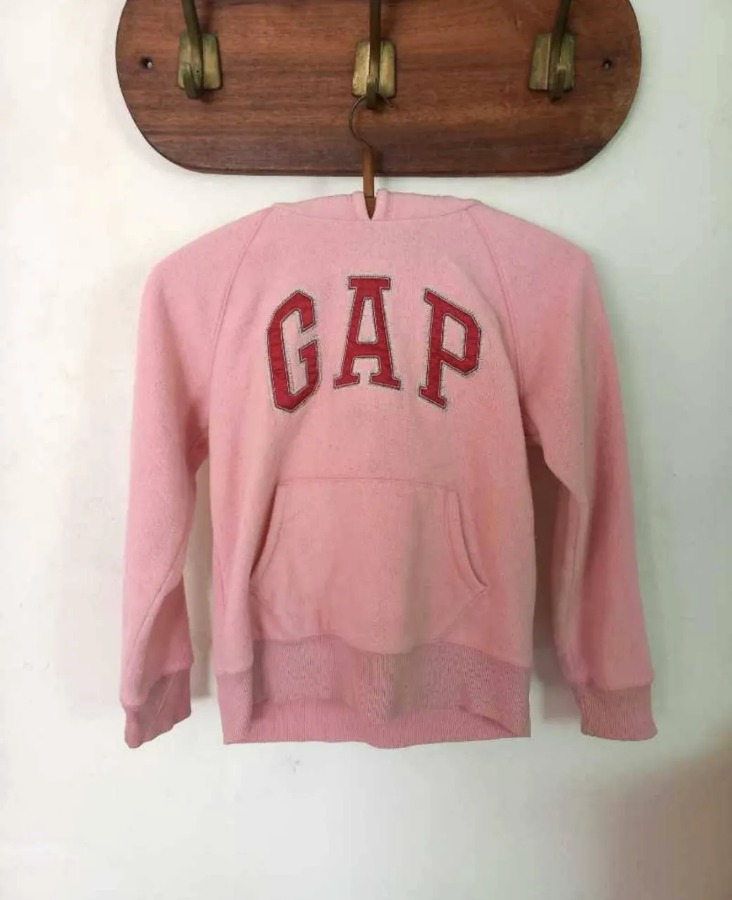 Buzo canguro rosa de la marca GapKids, ideal para niñas. Confeccionado en un tejido suave y abrigado, este buzo presenta el logo de la marca en el frente. Perfecto para un look casual y cómodo.