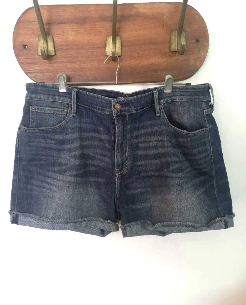 Short de jean azul de tiro alto, con detalles deshilachados en el borde. Ideal para un look casual y cómodo.