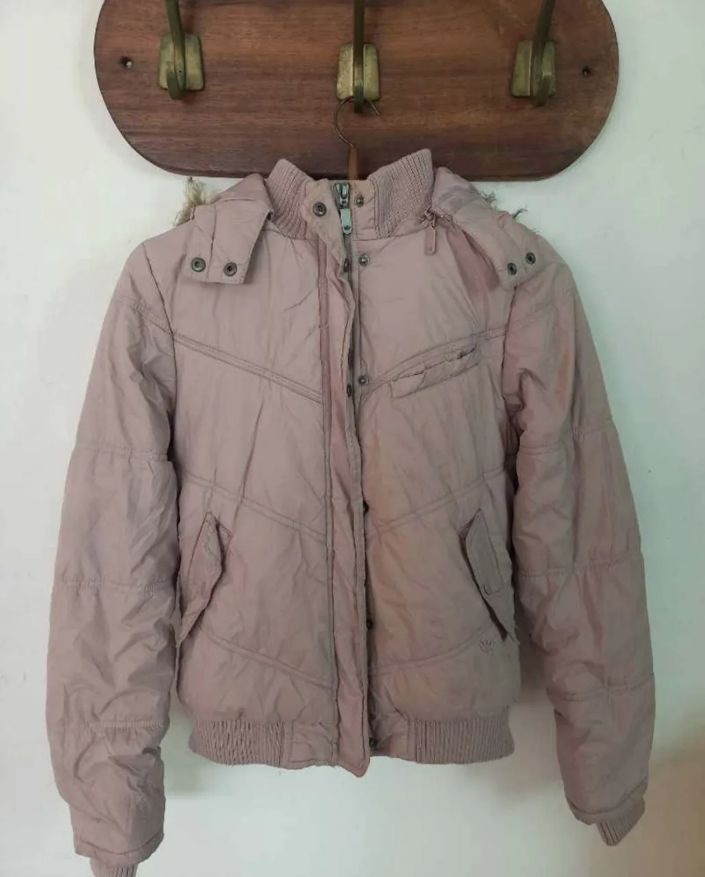 Campera acolchada rosa con capucha de piel sintética. Ideal para el frío, con bolsillos y cierre al frente. Un básico para tu guardarropa de invierno.