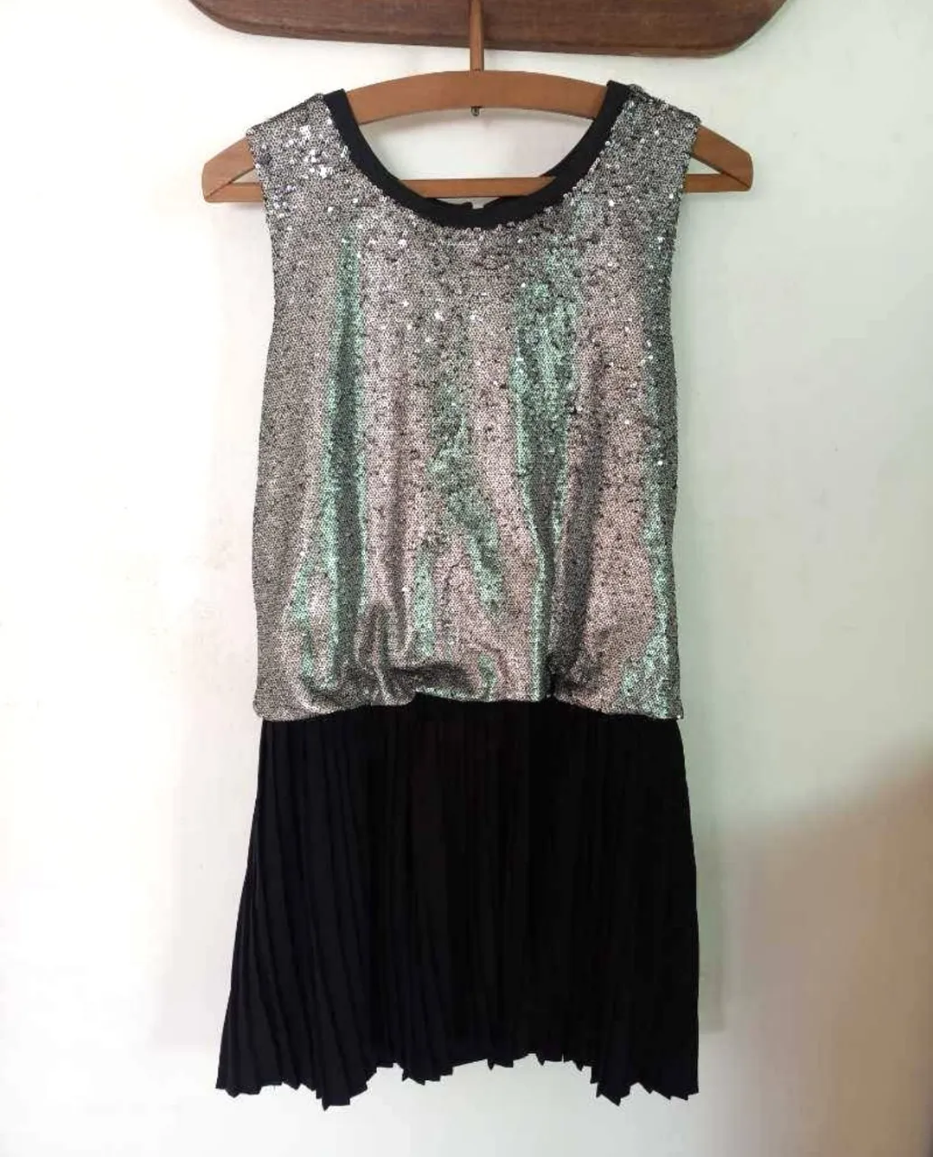 Vestido de fiesta con lentejuelas plateadas y falda plisada negra. Tiene forro de jersey y elástico en la cintura. Ideal para eventos especiales y salidas nocturnas.