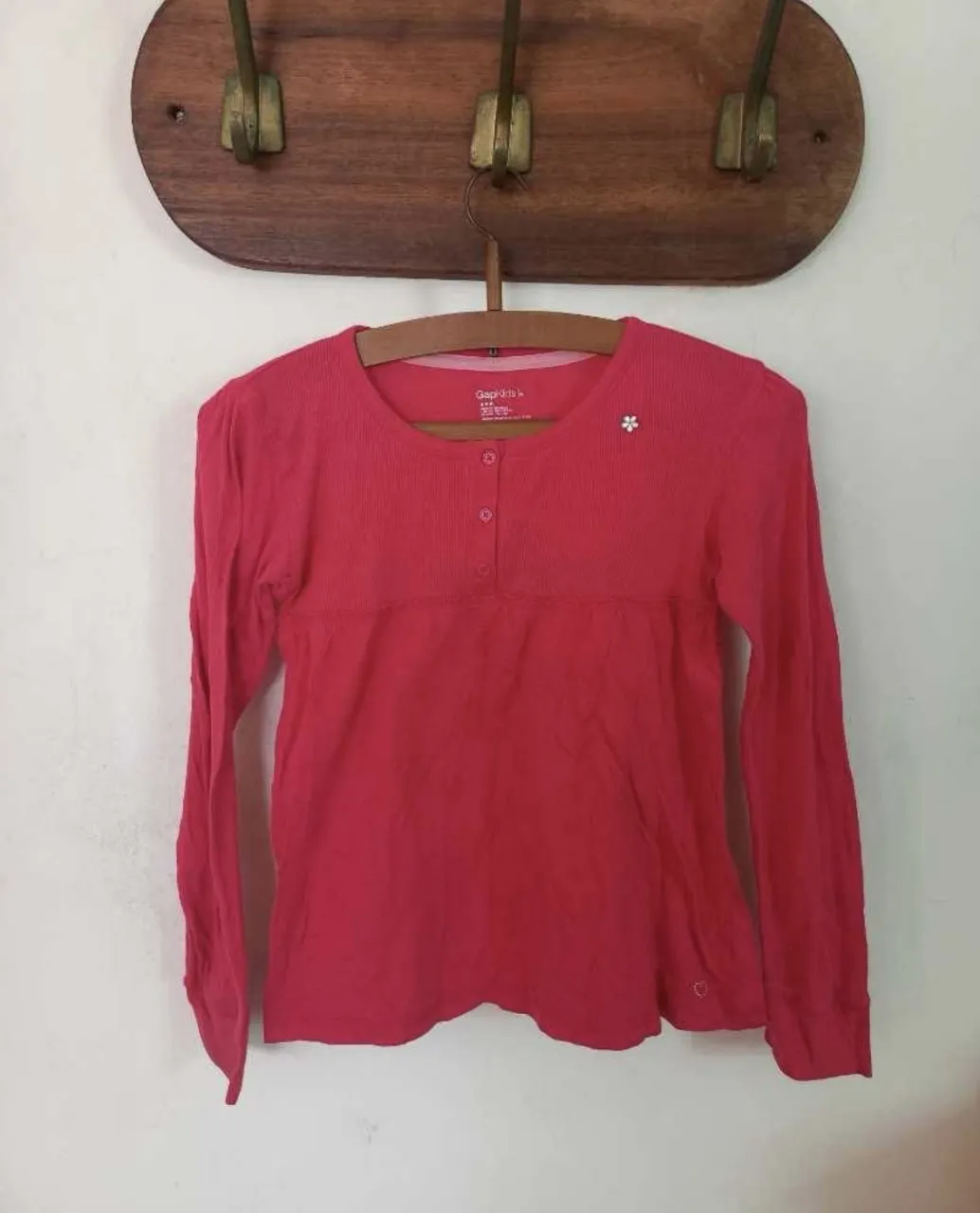 Remera manga larga rosa de GapKids con botones en el cuello y un pequeño aplique de flor. El único detalle es un agujerito chiquito en una de las mangas (se puede ver en la última foto). Ideal para el día a día.