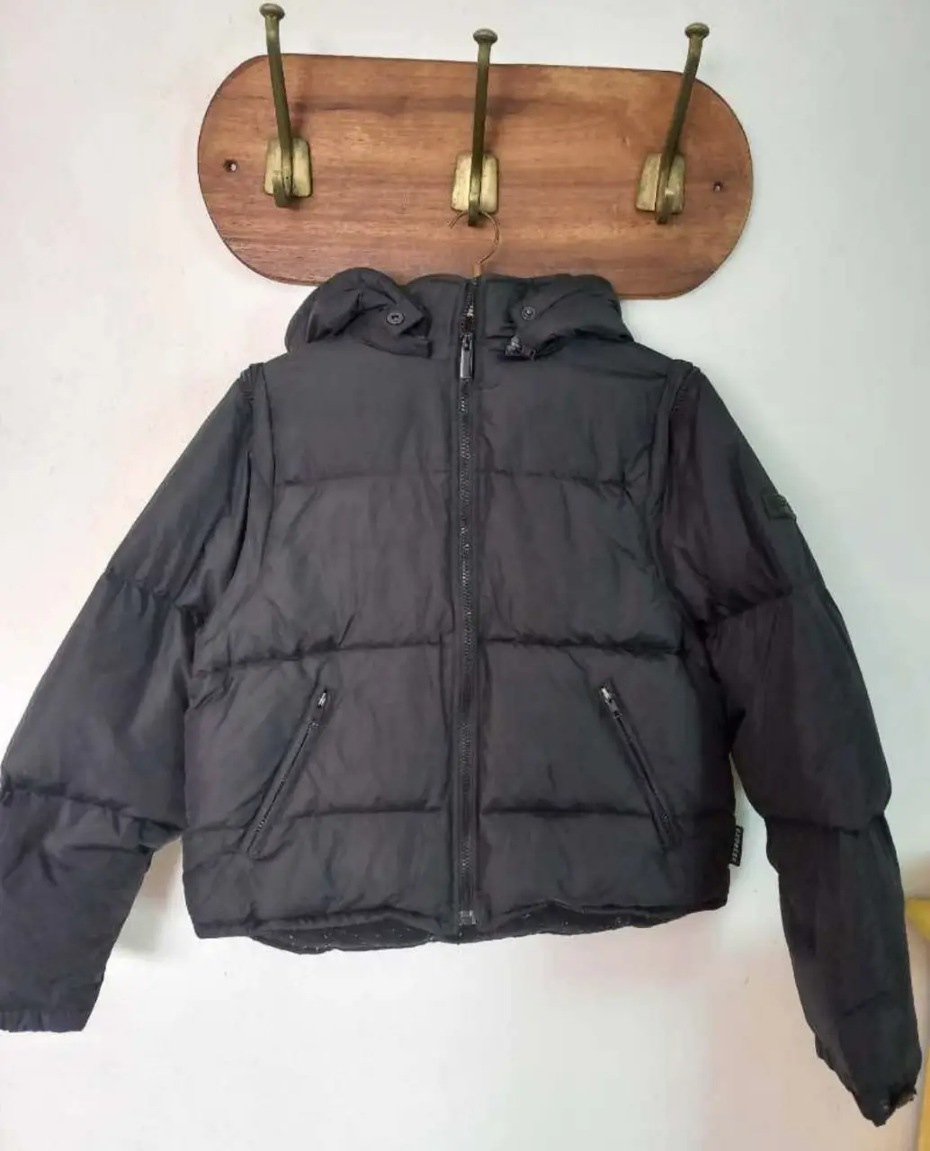 Campera de pluma negra Express, con capucha y cierre. Mangas desmontables por lo que se puede convertir en chaleco. Ideal para el invierno, abrigada y cómoda. Talle S.