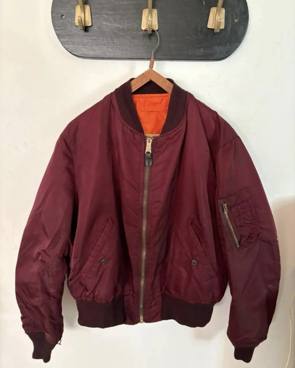 Campera bomber de color borravino con interior naranja. Ideal para un look retro y canchero. Pequeño agujero en uno de sus puños y pequeñas manchas de pintura en el interior. 