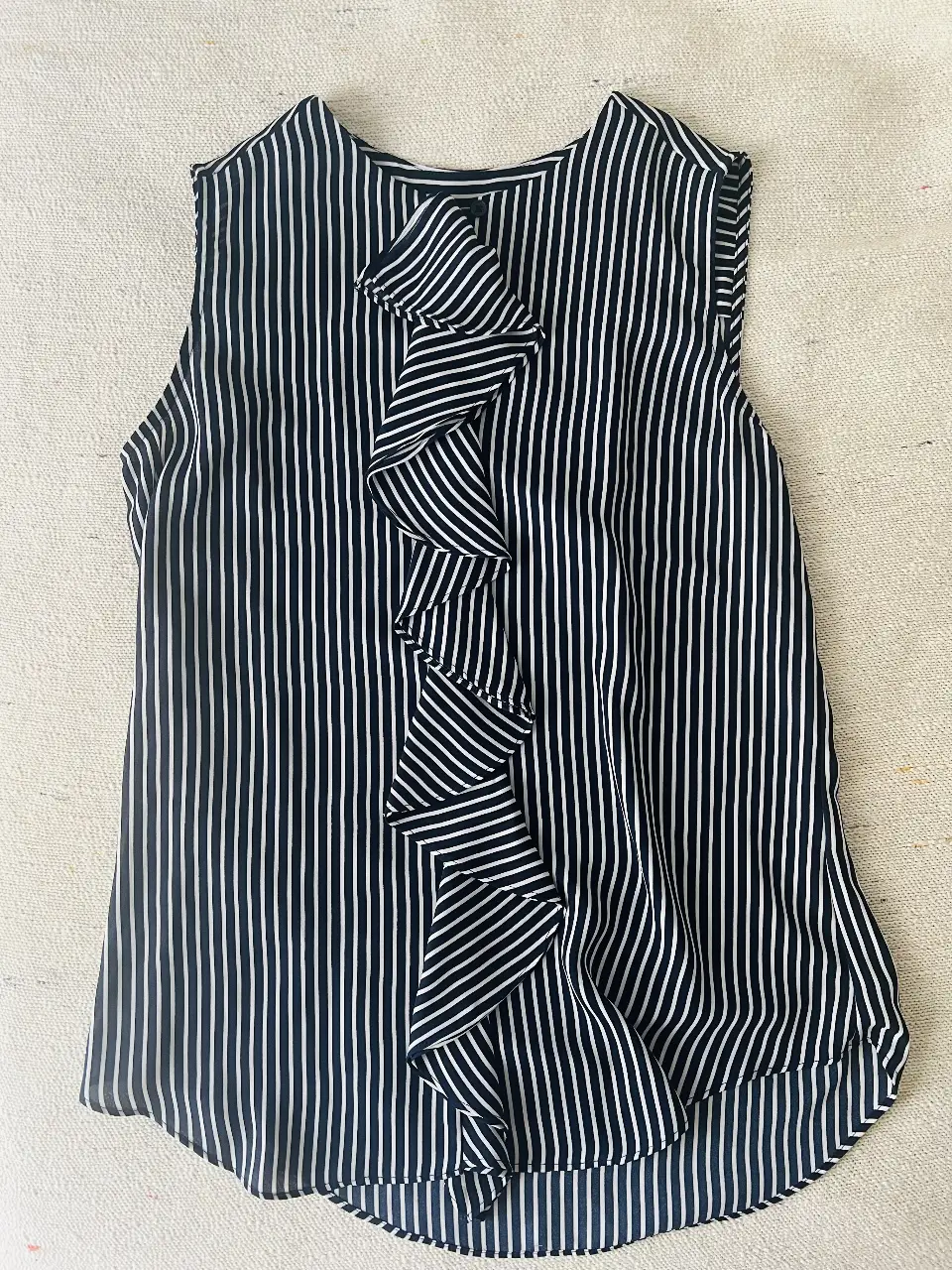Blusa Tommy Hilfiger a rayas verticales en blanco y azul marino, con detalle de volantes en el frente. Ideal para un look elegante y fresco.