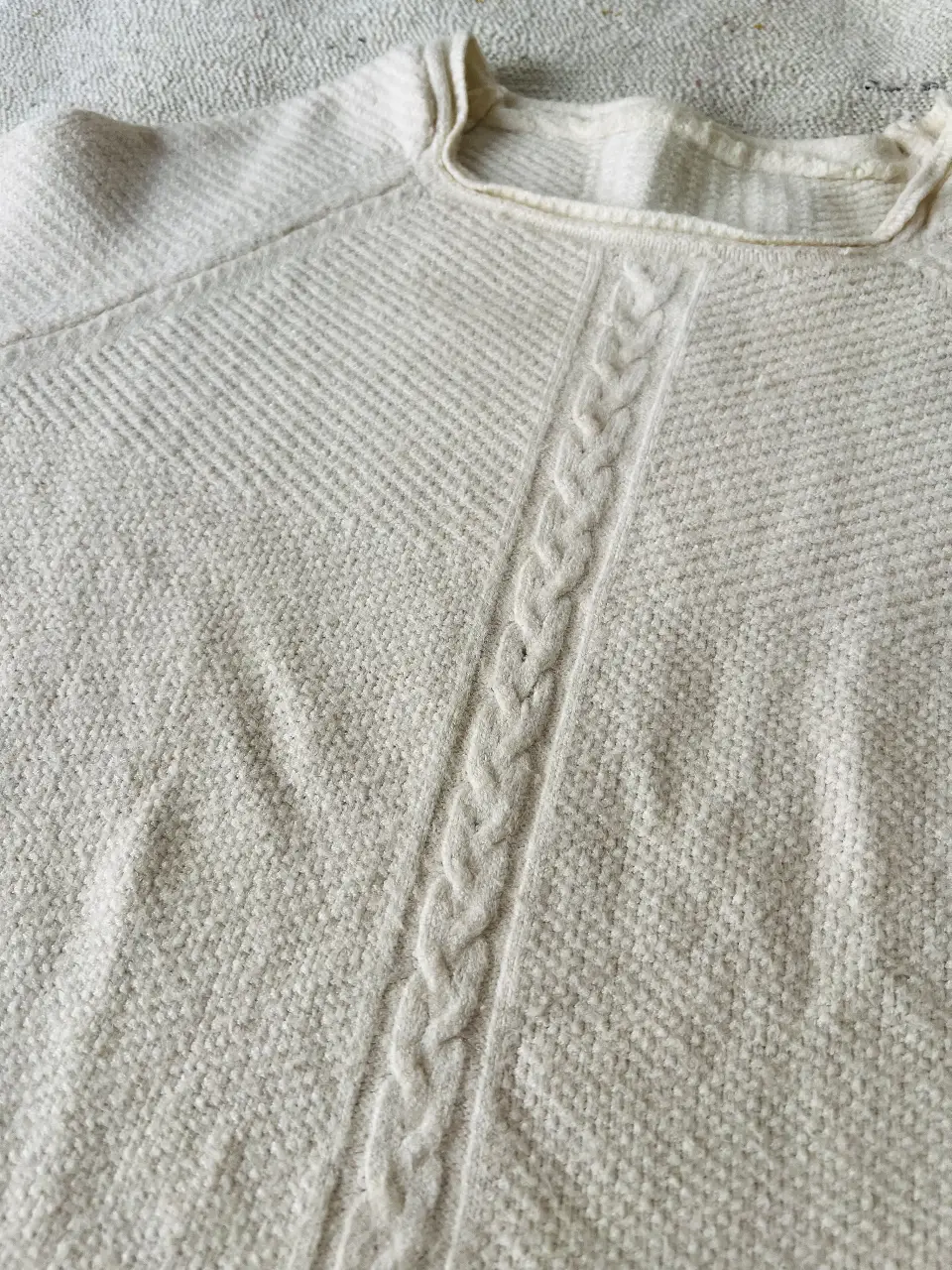 Sweater largo de punto color blanco con detalle de trenza central. Cuello cuadrado y mangas ranglan. Ideal para un look casual y abrigado.