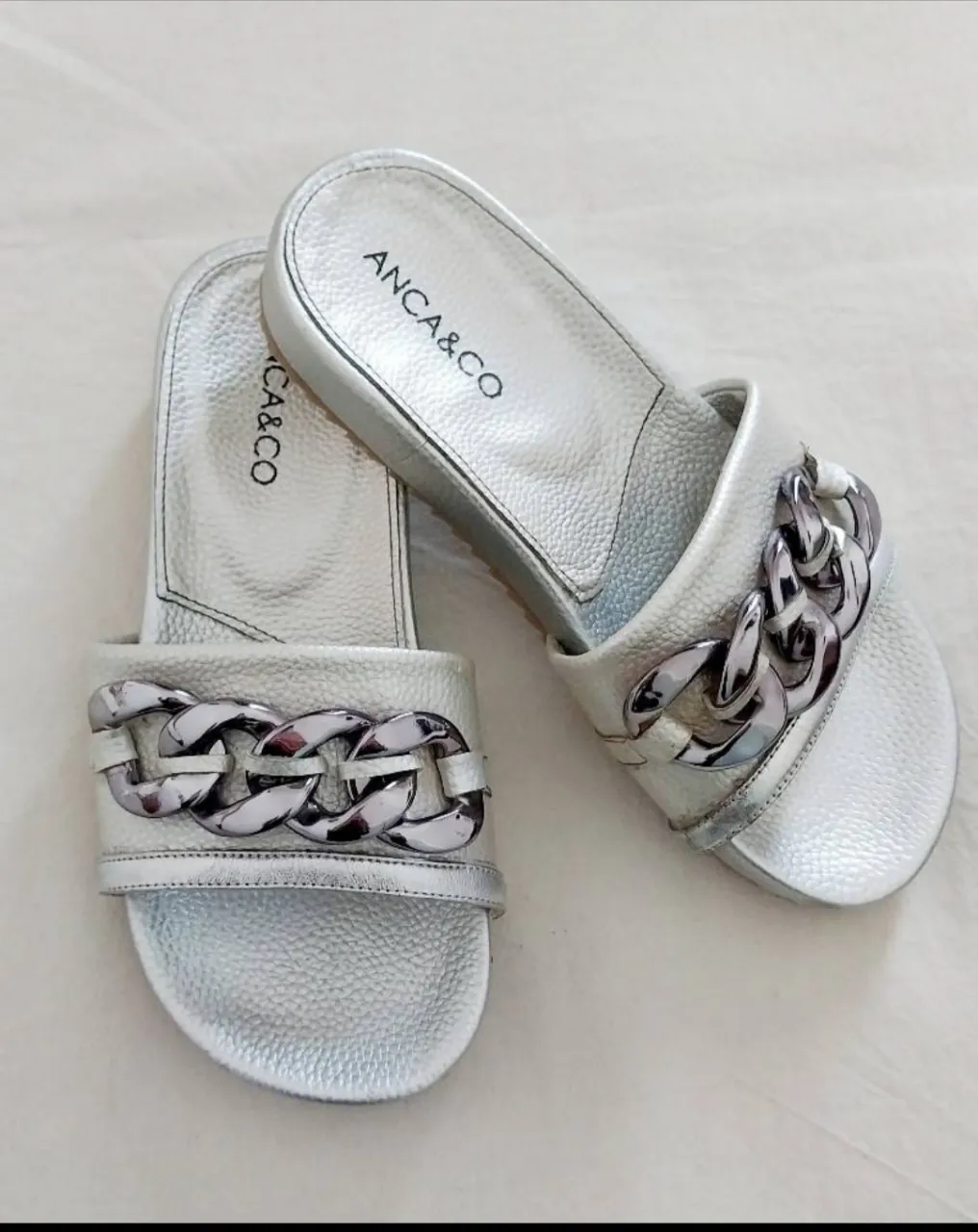 Sandalias plateadas con detalle de cadena metálica gruesa en la tira superior.  Talle 36 horma chica. Medida de plantilla 23 cm. 