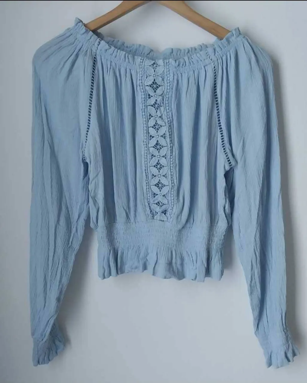 Blusa celeste con detalles de encaje en el centro y en los laterales. Tiene mangas largas con puños y un corte a la cintura con elástico. Marca H&M. Talle 38, Va para un L aprox. Medidas de pecho: 46 cm . 