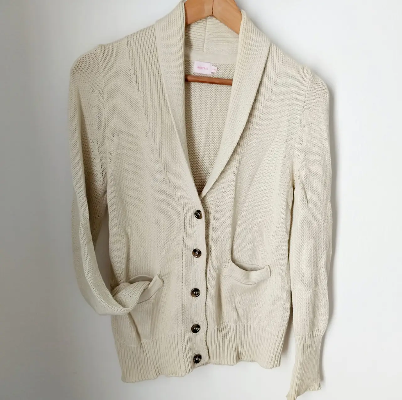 Cardigan de mujer color crudo, con botones y bolsillos. 