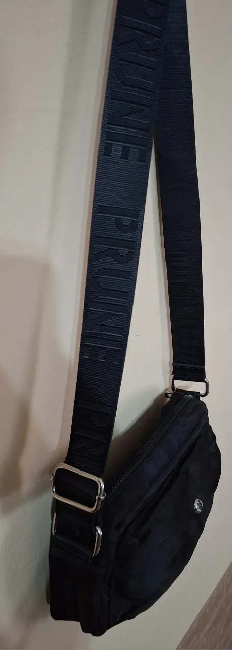 Bandolera negra con correa ancha y ajustable con logo en relieve. Cierre principal con cierre.