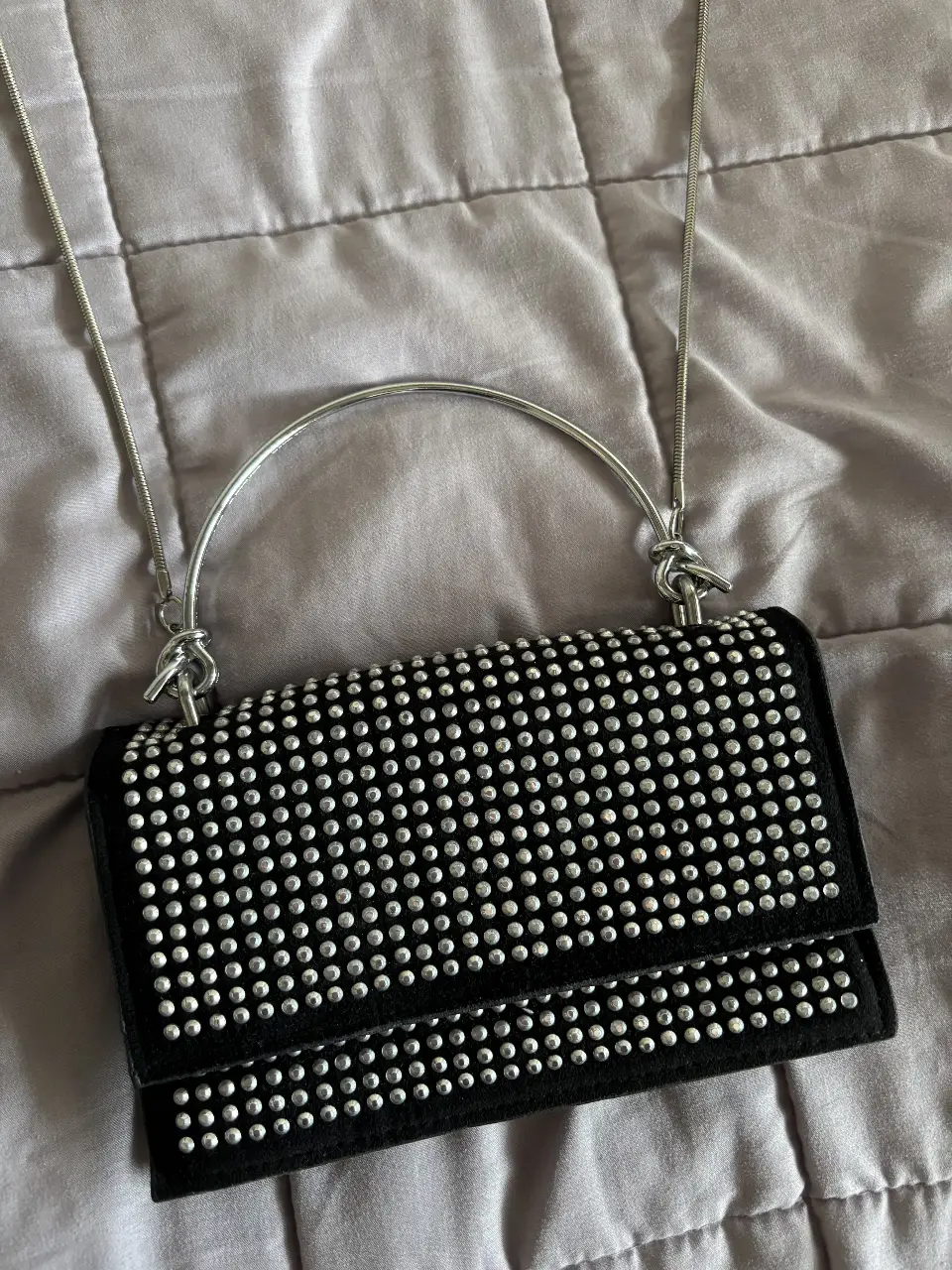 Cartera bandolera negra con tachas plateadas. Diseño elegante y moderno, ideal para fiestas y salidas.