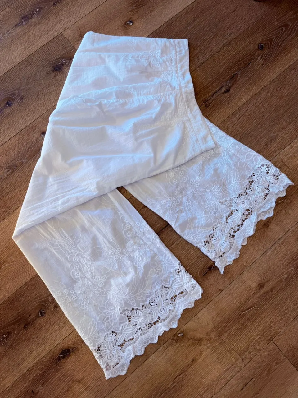 Pantalón blanco con bordados florales y detalles de encaje en los bajos. Posee un botón en la cintura.