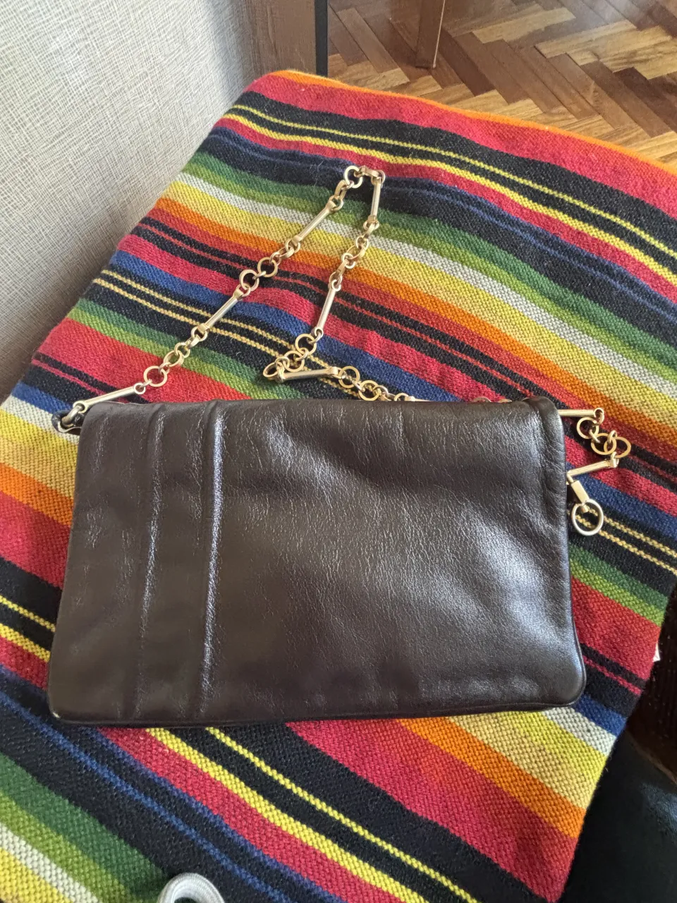 Cartera de cuero marrón con cadena dorada.