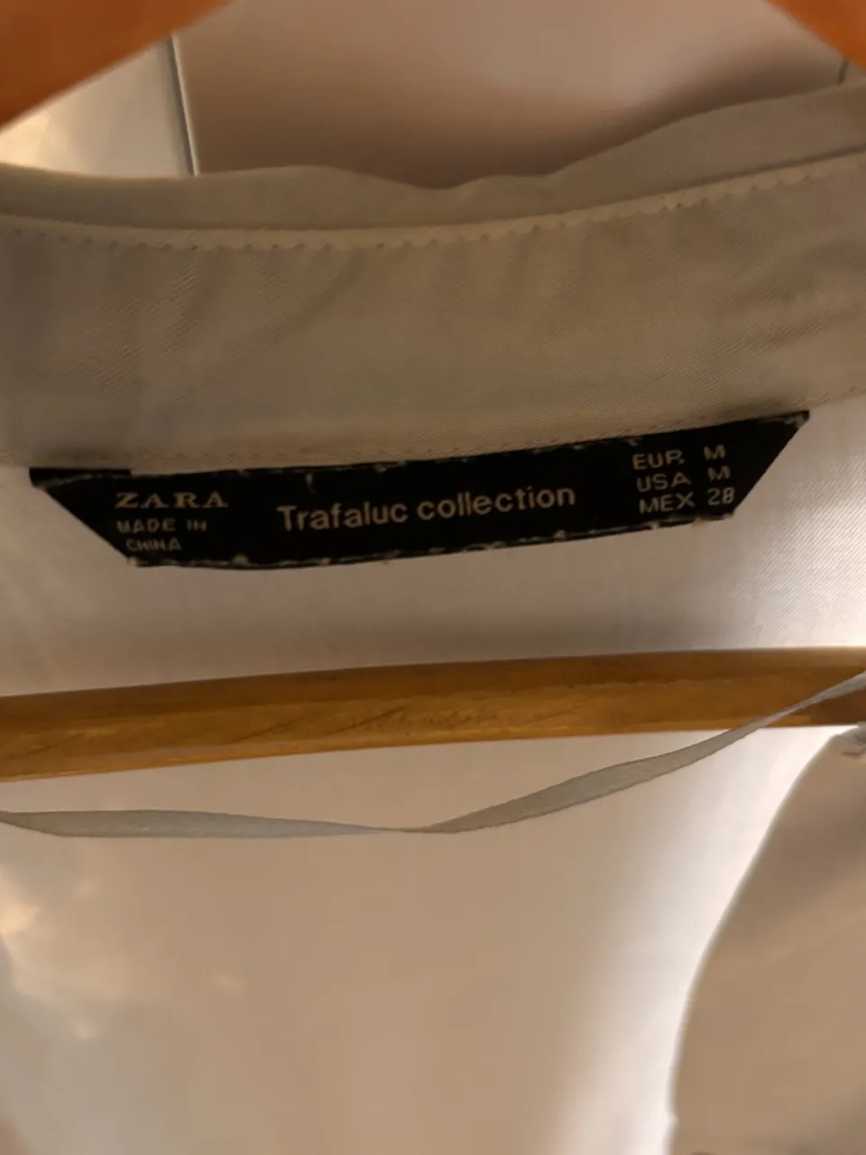 Camisa blanca de manga larga con dos bolsillos en el frente. Cierre de botones.