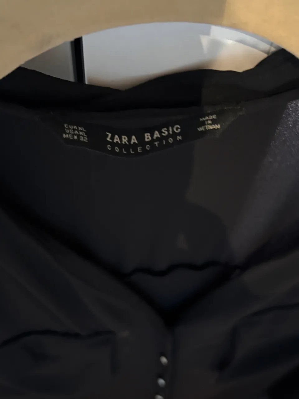 Camisa negra de manga larga con botones al frente. Posee cuello y detalle de bolsillos en el frente.