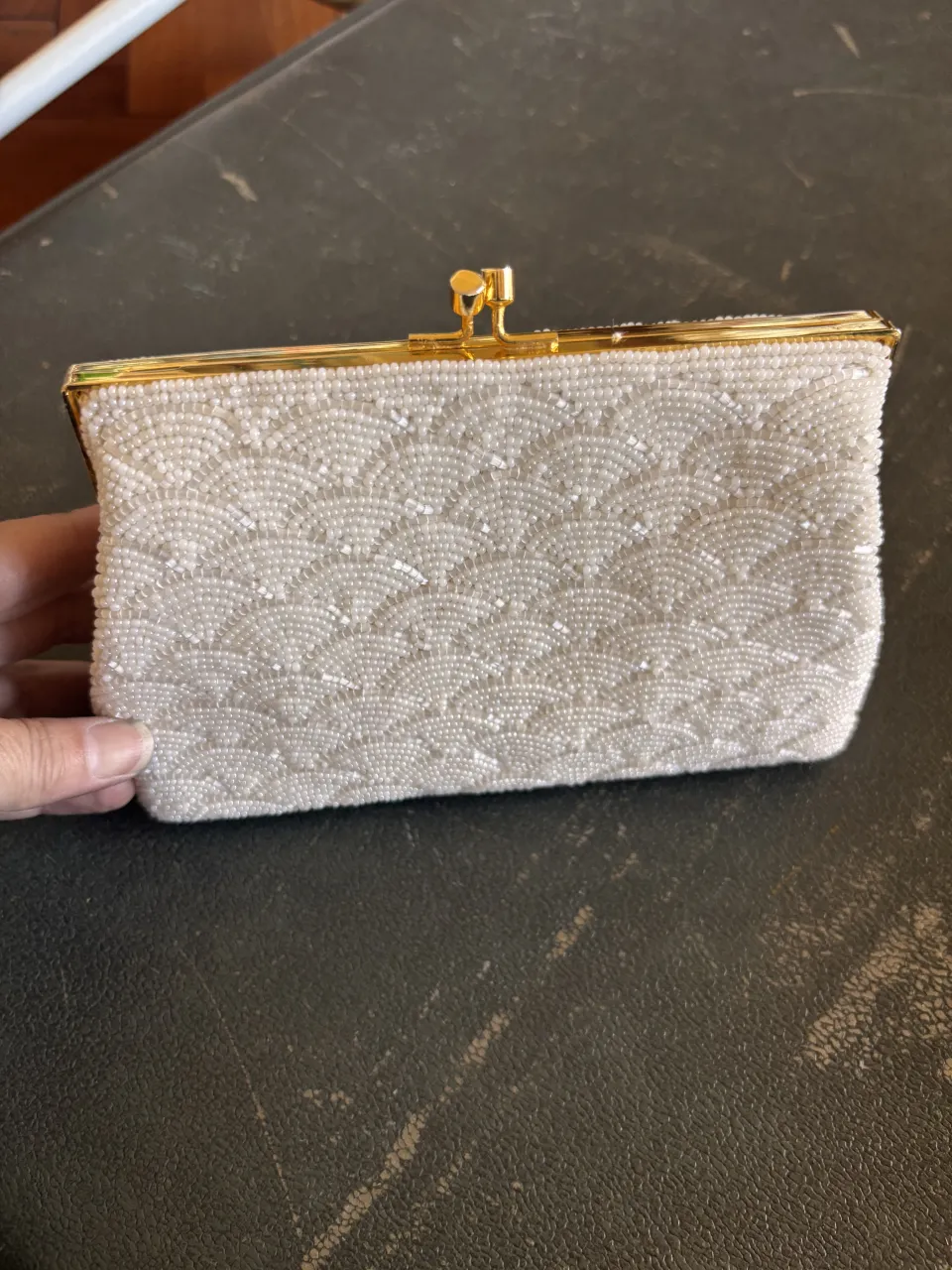 Cartera de mano blanca, completamente bordada con pequeñas cuentas. Posee un cierre metálico dorado y una cadena fina dorada para llevar al hombro.
