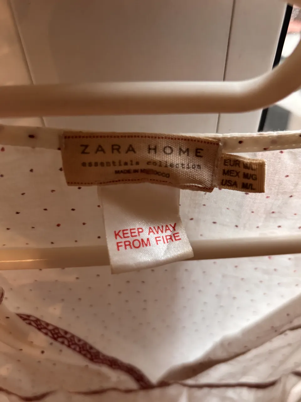 Blusa blanca con pequeños lunares rojos y detalles bordados en la parte inferior y en el escote. Posee mangas largas.