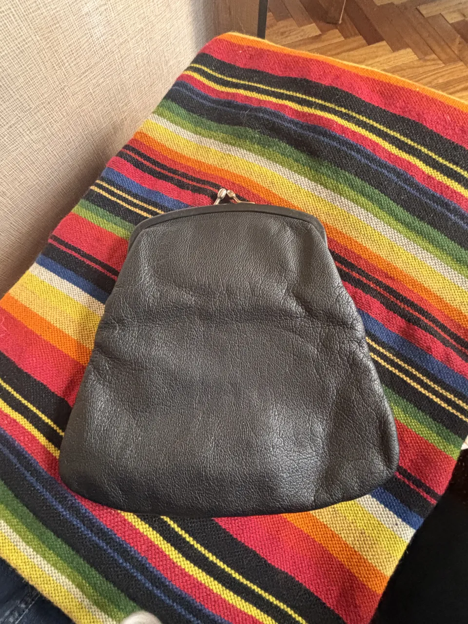 Cartera tipo monedero de cuero negro con cierre metálico.