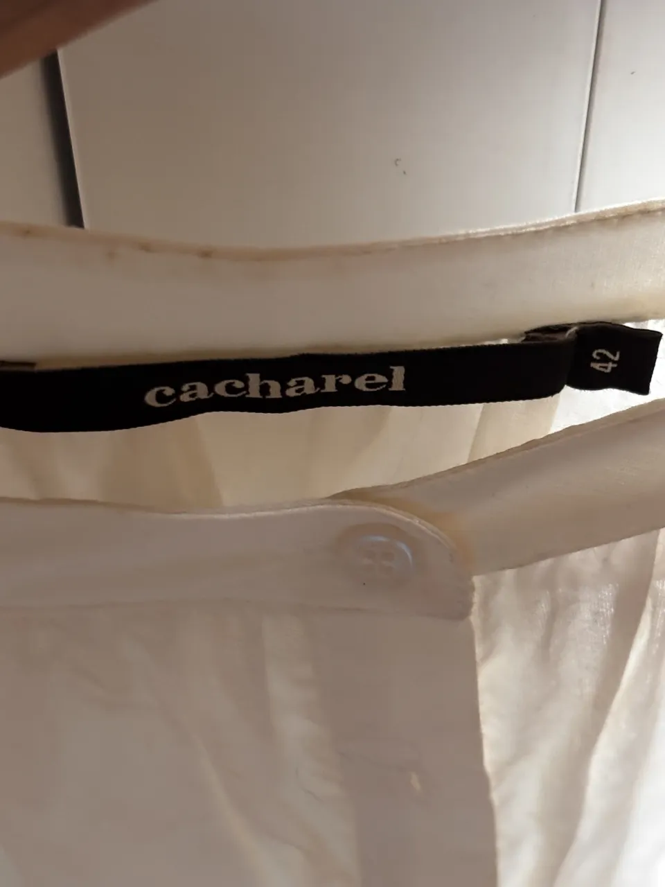 Blusa blanca de manga larga con detalles bordados en las mangas y en el ruedo. Posee cuello redondo con botones al frente.