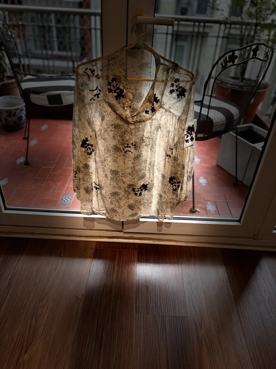 Blusa de seda estampada con flores y detalles bordados en negro y rojo. Posee mangas largas y volado en el ruedo.