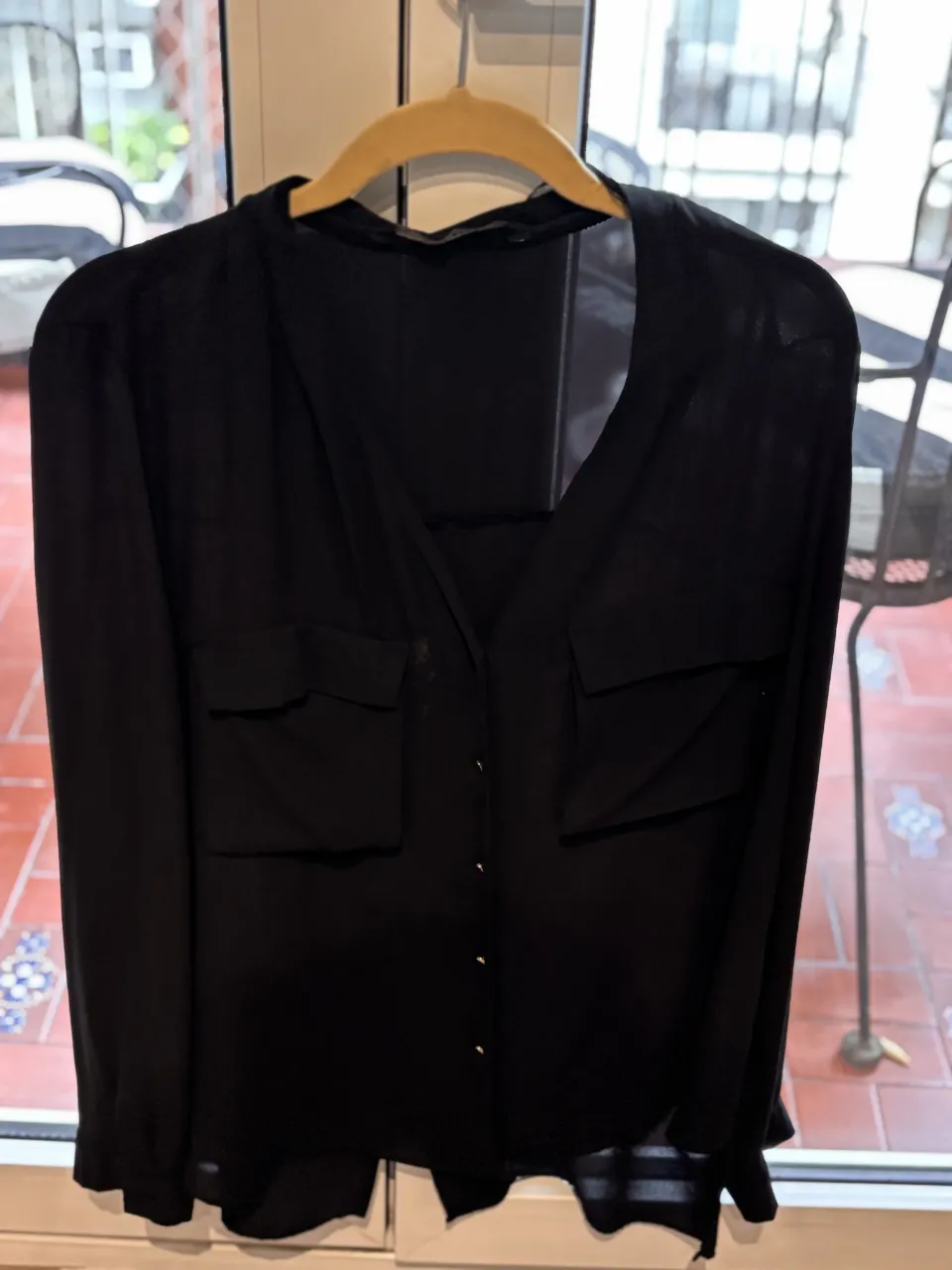 Camisa negra de manga larga con botones al frente y dos bolsillos en el pecho.