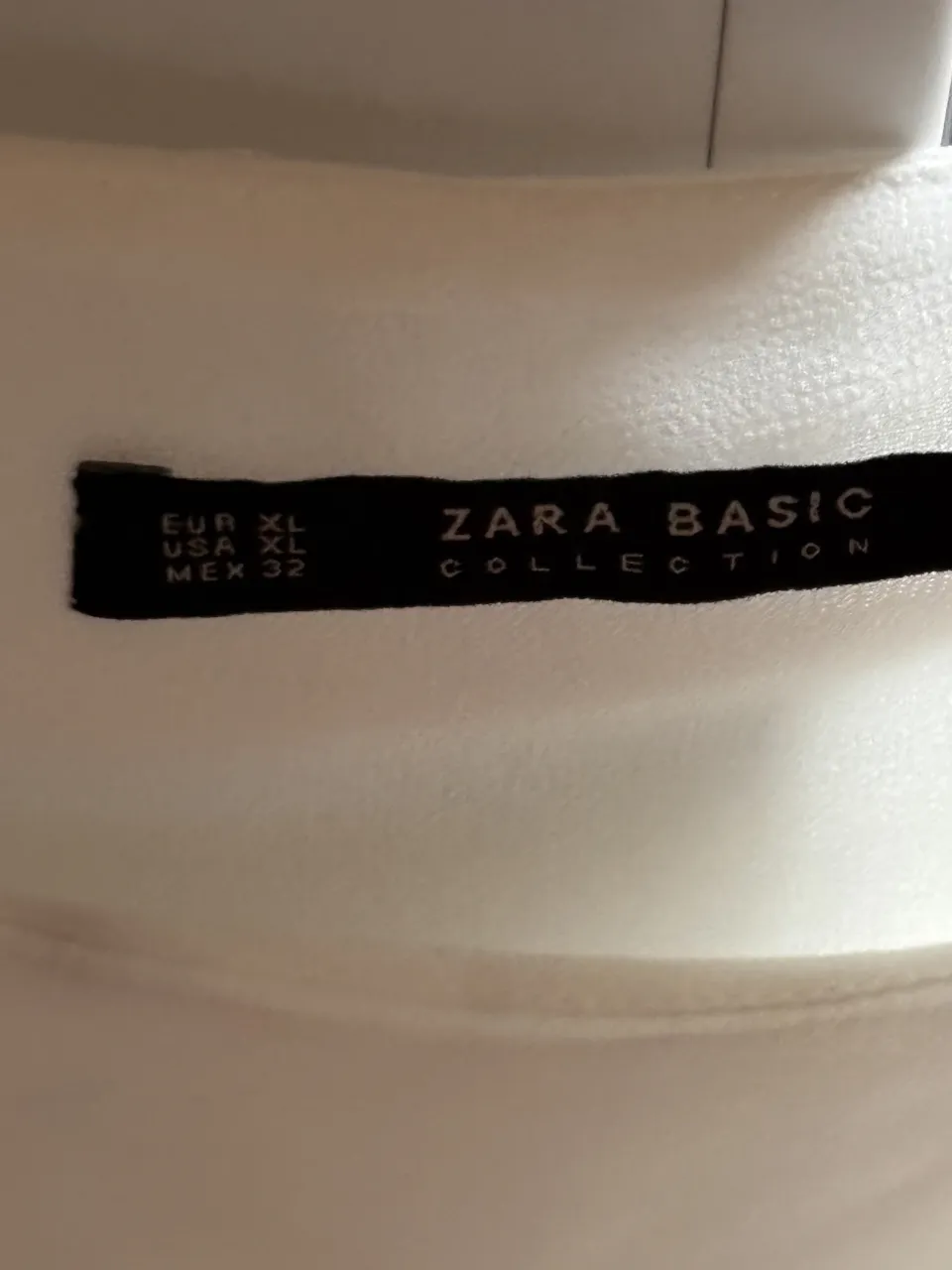 Blusa blanca de manga larga con detalles de encaje en el ruedo.