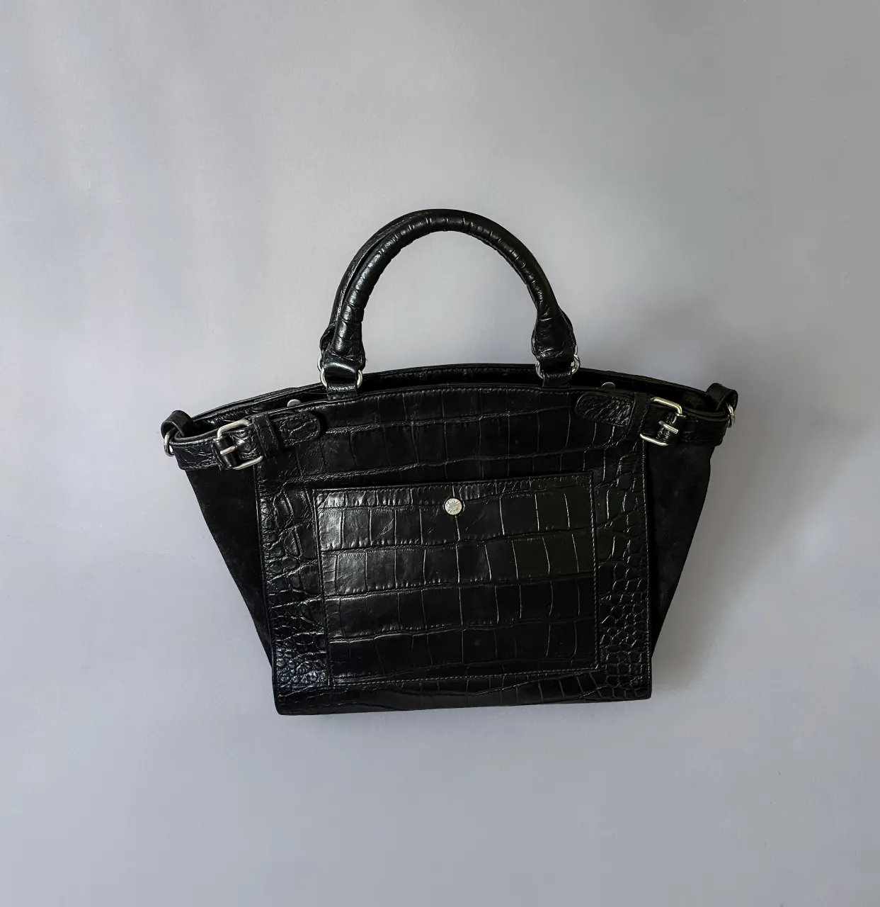 Cartera Prüne de mano de cuero con textura de cocodrilo y detalles en gamuza. Posee correa desmontable para llevar cruzad. Muy poco uso.