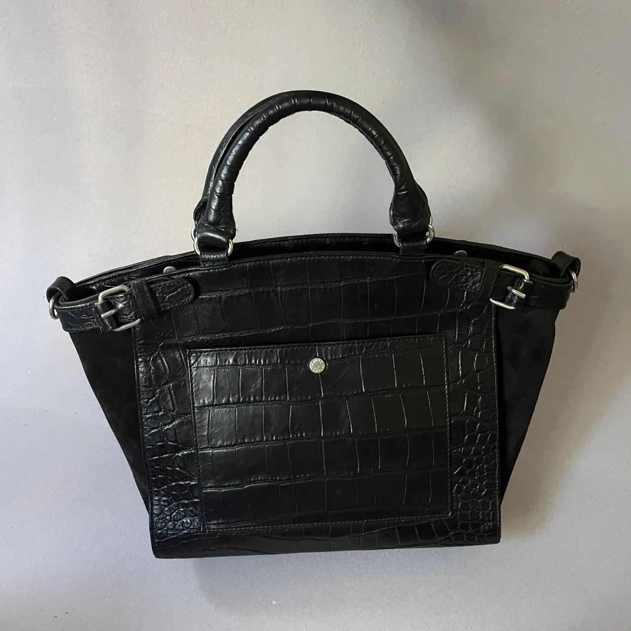 Cartera Prüne de mano de cuero con textura de cocodrilo y detalles en gamuza. Posee correa desmontable para llevar cruzad. Muy poco uso.