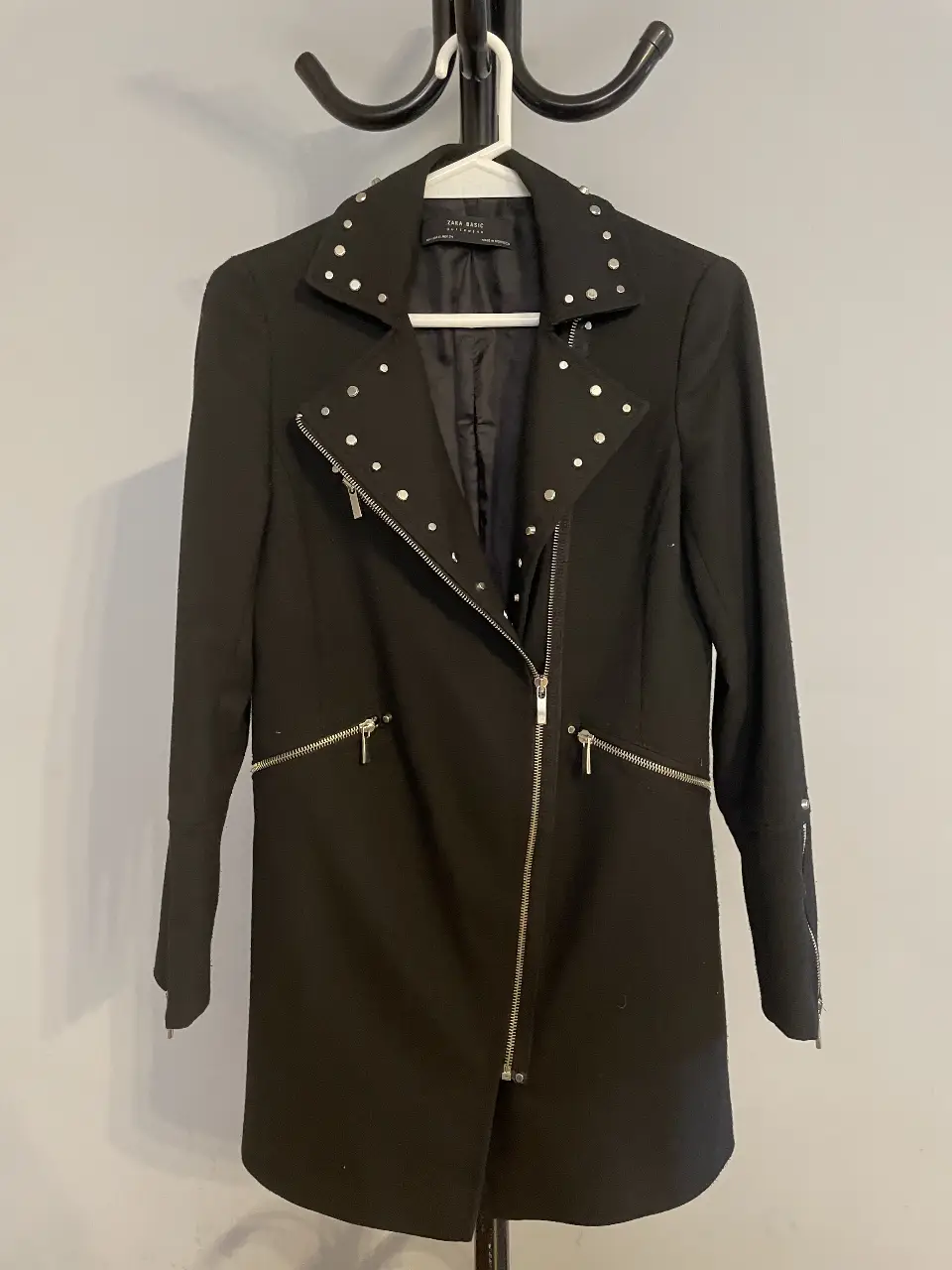 Tapado negro sastrero muy canchero de Zara Basic, con detalles de tachas plateadas en cuello y hombros. Posee cierre y bolsillos con cierres metálicos. Talle XS. La tela esta un poco gastada y el interior de uno de los bolsillos está roto. 