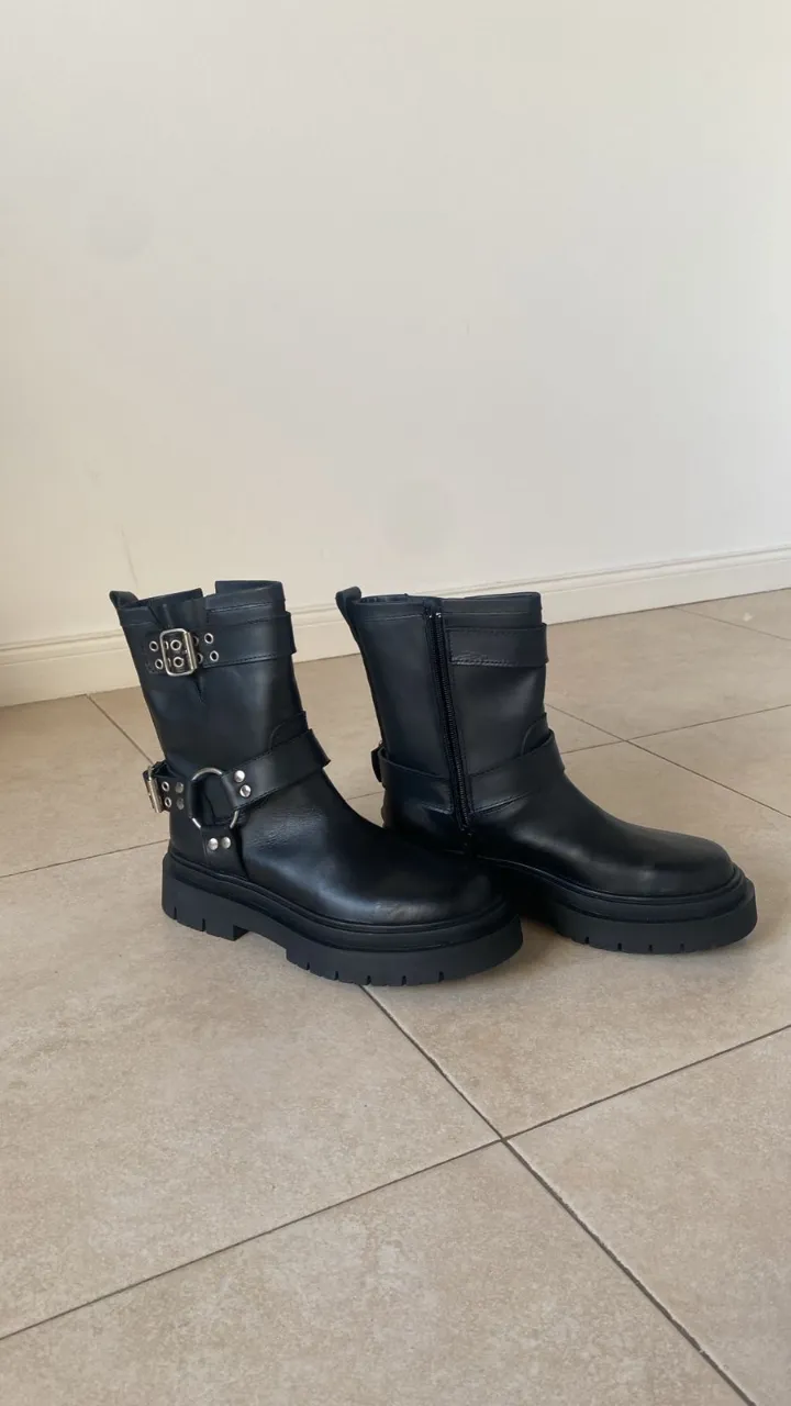Borcegos de cuero negro con hebillas y detalles metálicos. Suela gruesa y cierre lateral. Ideales para un look urbano y canchero.
