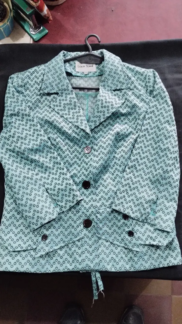 Blazer de mujer con estampado de círculos en tono celeste. Posee dos bolsillos delanteros, botones y un lazo en la parte trasera para ajustar la cintura. Ideal para un look elegante y sofisticado.