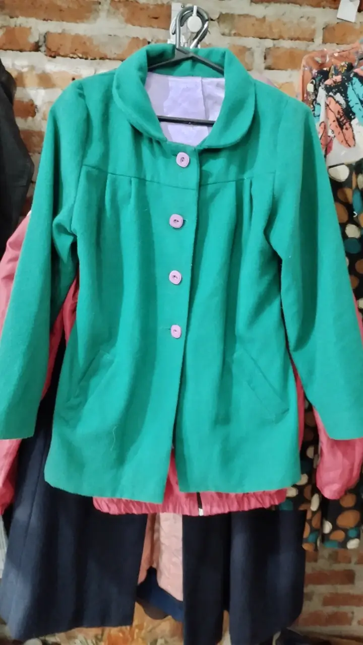 Chaqueta verde con botones rosas, ideal para un look elegante y moderno. Perfecta para combinar con diferentes outfits.