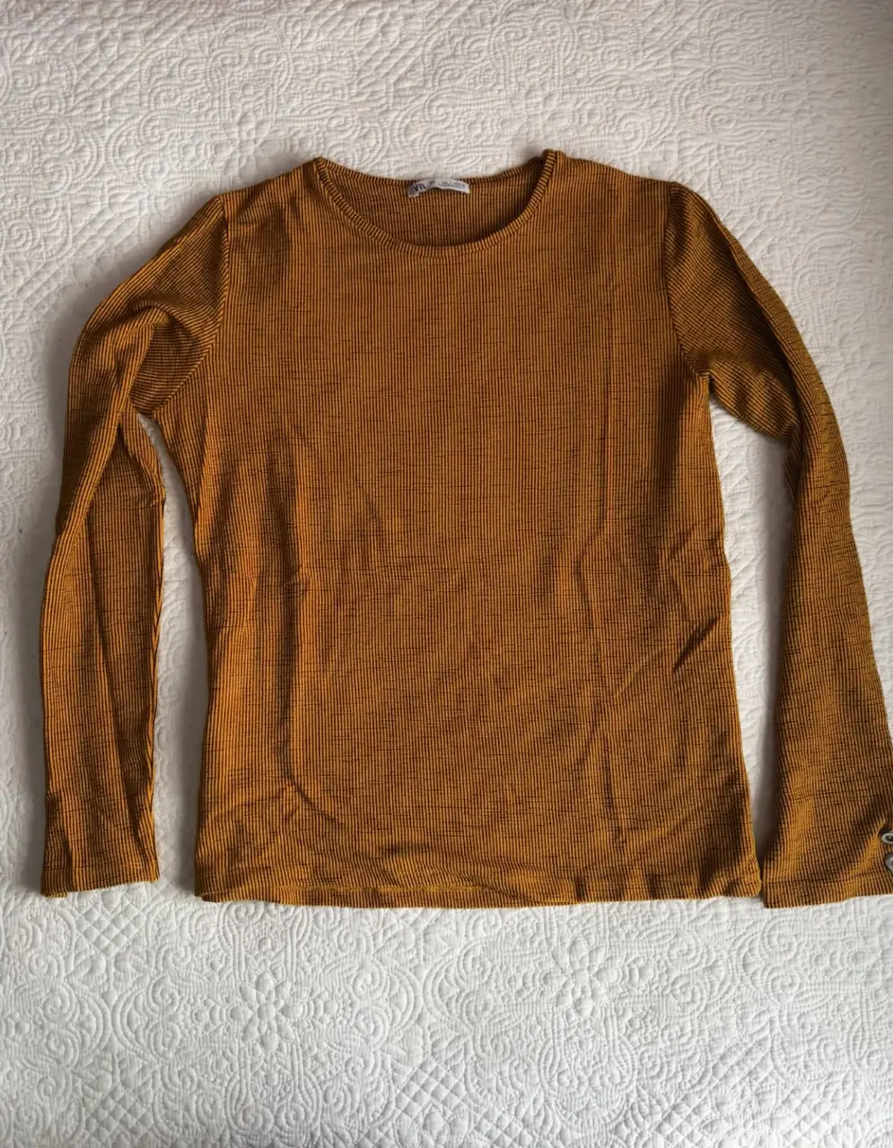 Remera manga larga de tejido acanalado en color mostaza. Lineas negras. Cuello redondo y detalle de botones en los puños. Talle L de Zara.