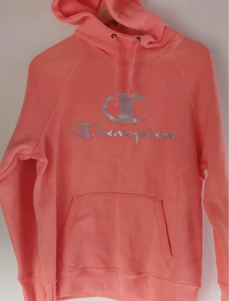 Buzo canguro Champion rosa con logo plateado. Talle L. Ideal para un look casual y cómodo.