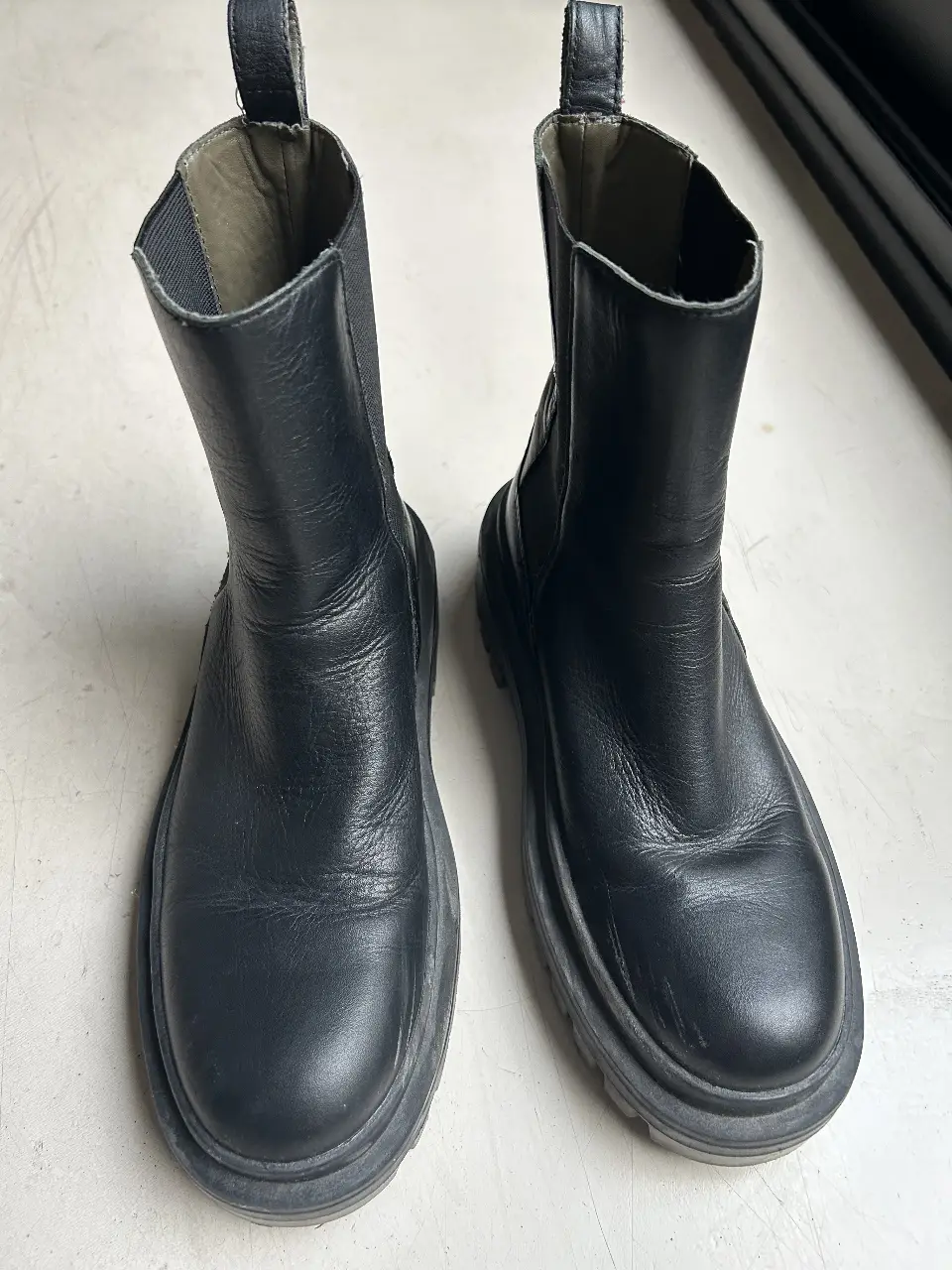 Botas negras de cuero con suela gruesa, ideales para un look urbano y moderno. Perfectas para el invierno, combinan estilo y comodidad.