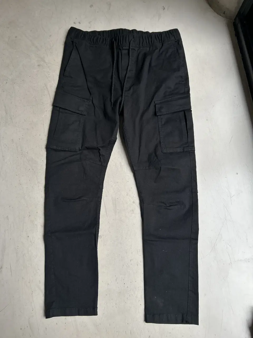 Pantalón cargo negro para hombre, con bolsillos laterales y cintura elastizada con cordón. Ideal para un look casual y cómodo.