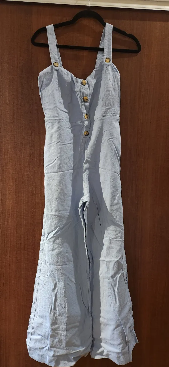 Mono largo de tela liviana, color azul pastel. Posee breteles anchos con botones en la parte superior y un diseño de botones en el frente. La parte inferior es ancha y acampanada, ideal para un look fresco y canchero.