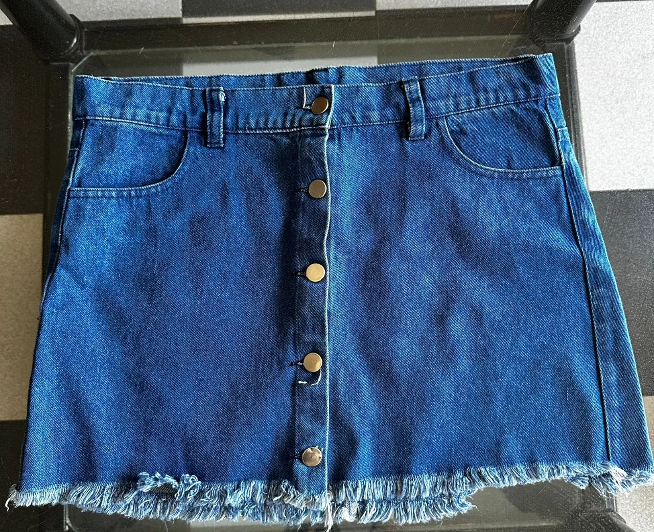 Pollera de jean tiro alto con botones al frente y tajos deshilachados en el ruedo. Un clásico que no puede faltar en tu guardarropa.