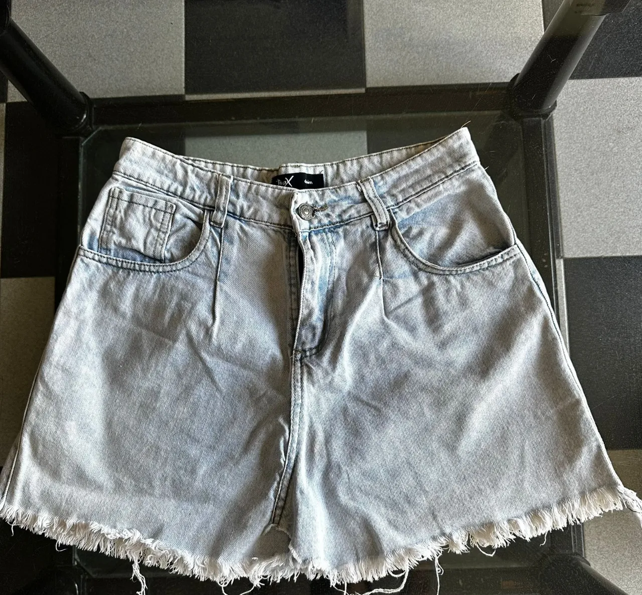 Shorts de jean tiro alto con roturas y detalles desflecados en el ruedo. Lavado claro y moderno, perfectos para un look casual y canchero.