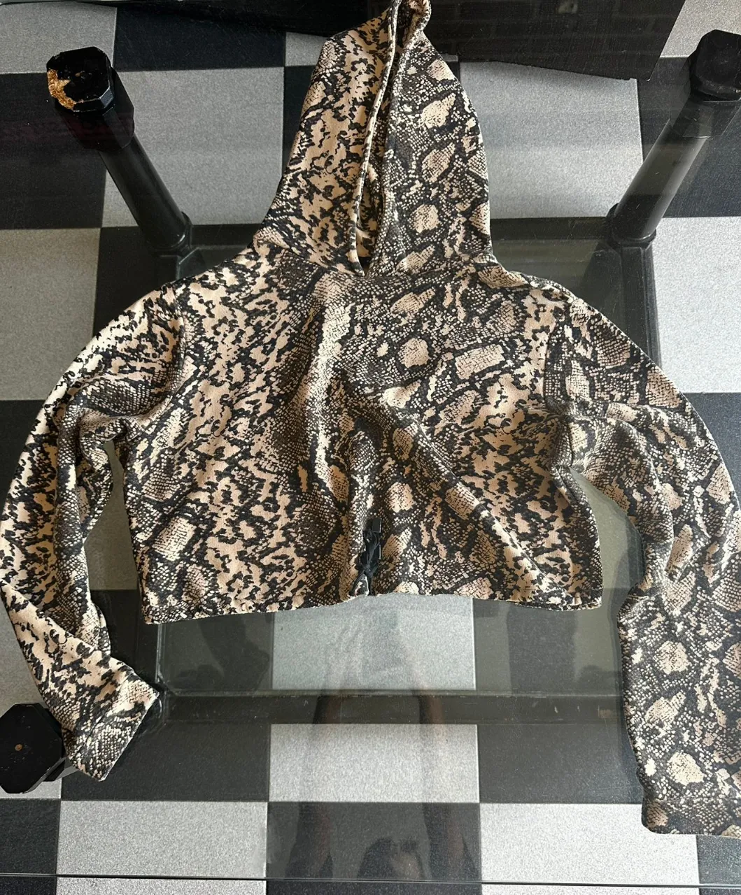 Remera con capucha y estampa de serpiente, estilo crop. Ideal para un look canchero y moderno.