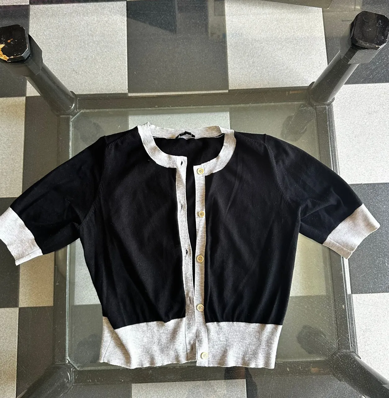 Cardigan corto de mangas cortas, color negro con detalles en gris. Ideal para un look casual y canchero.