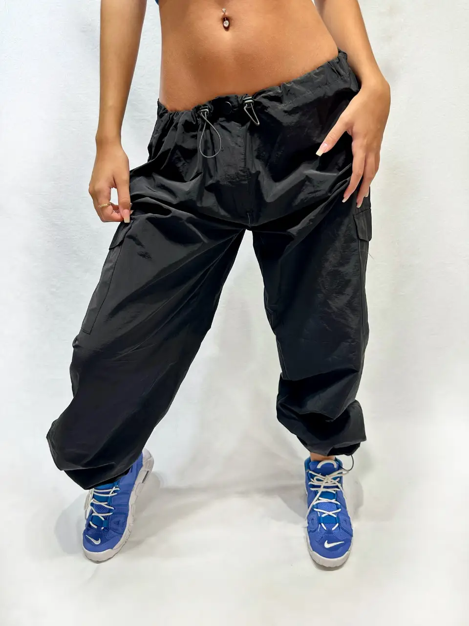 Pantalón cargo negro, tiro medio, con bolsillos laterales y ajuste en los tobillos. Ideal para un look urbano y cómodo.