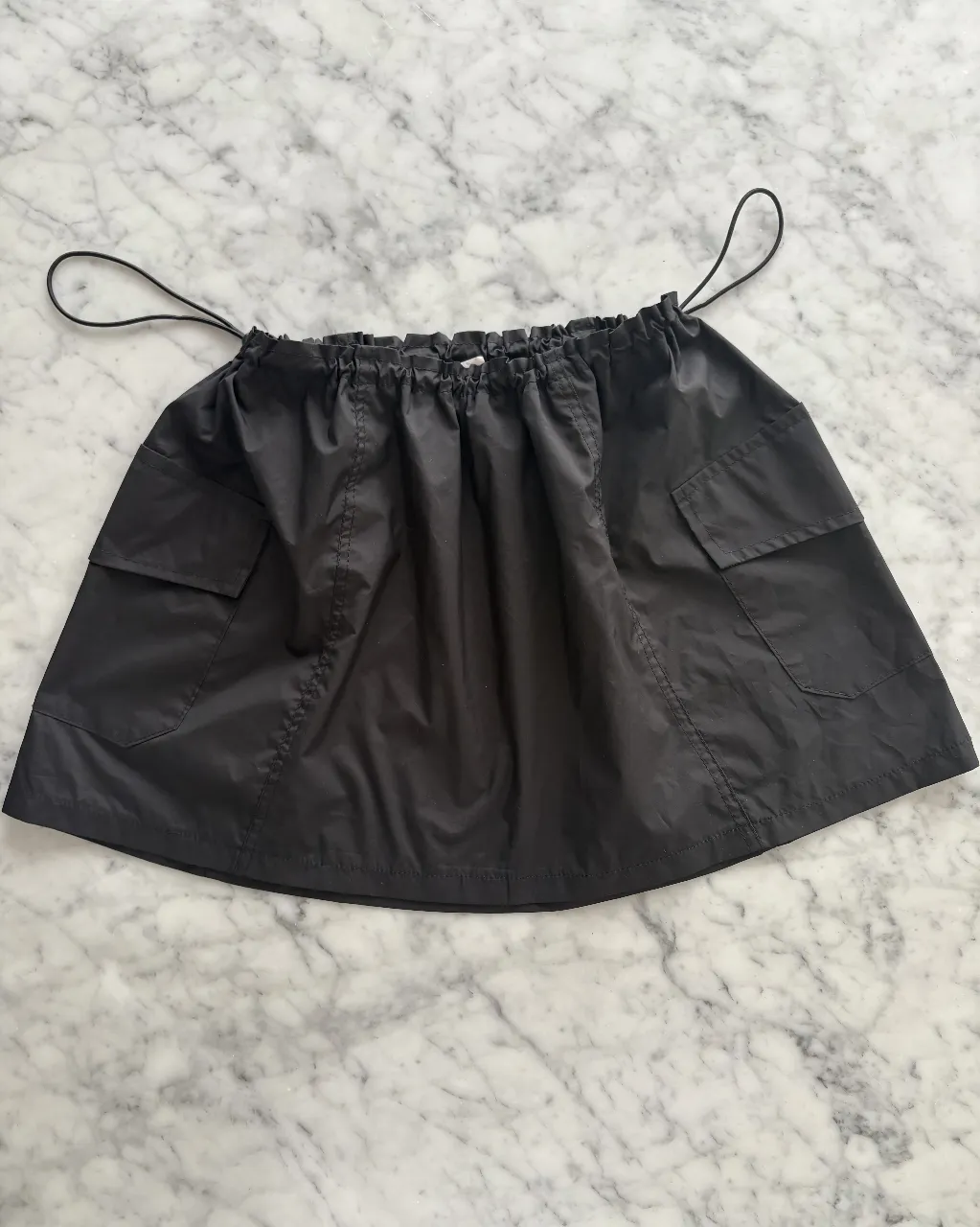 Pollera corta negra con bolsillos cargo y cordón ajustable en la cintura. Ideal para un look urbano y canchero. medidas de cintura sin ajustar 42 cm