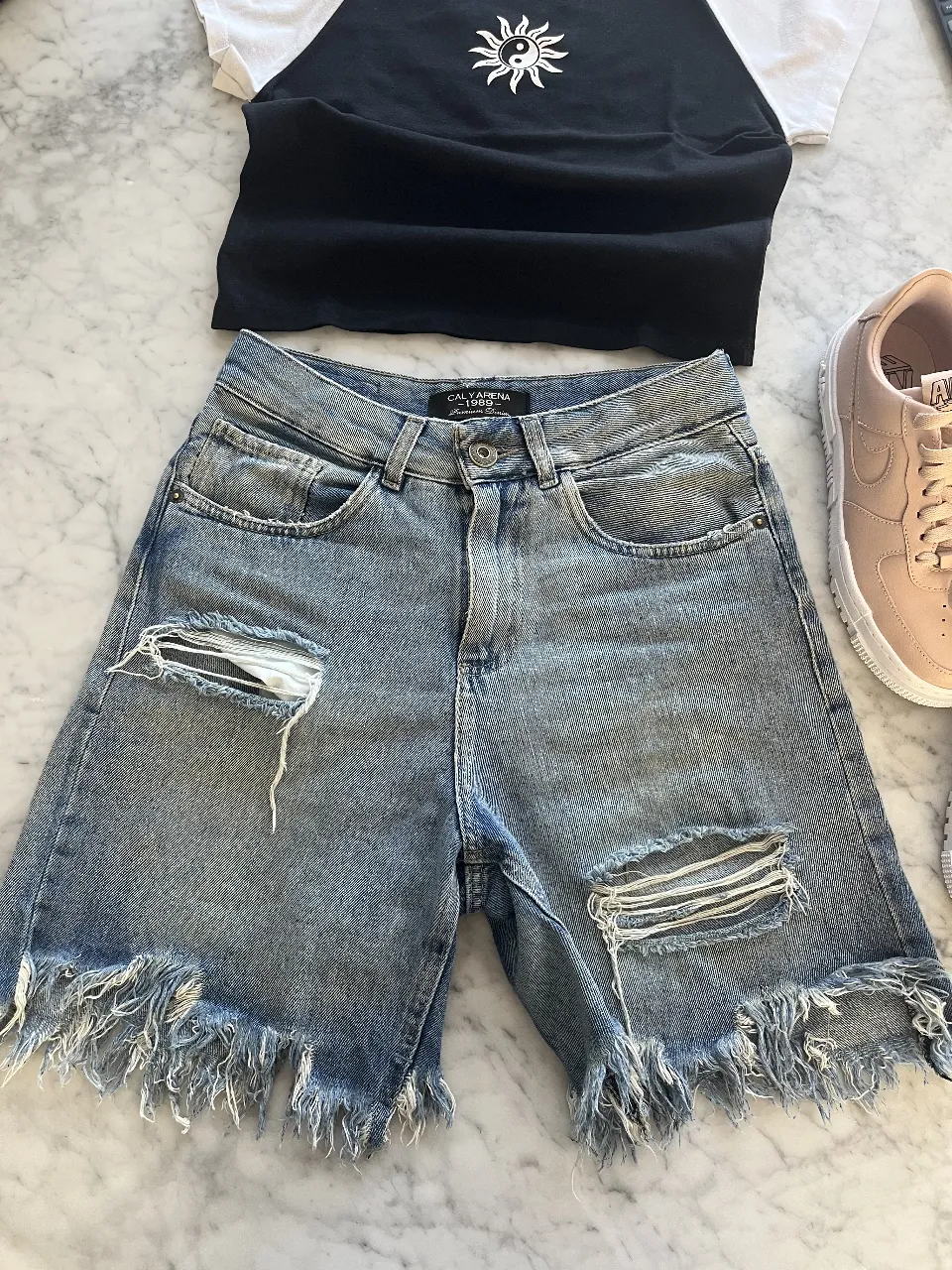 Shorts de jean tiro alto, con roturas y detalles desflecados en los bordes. Un básico canchero para armar looks informales y modernos.