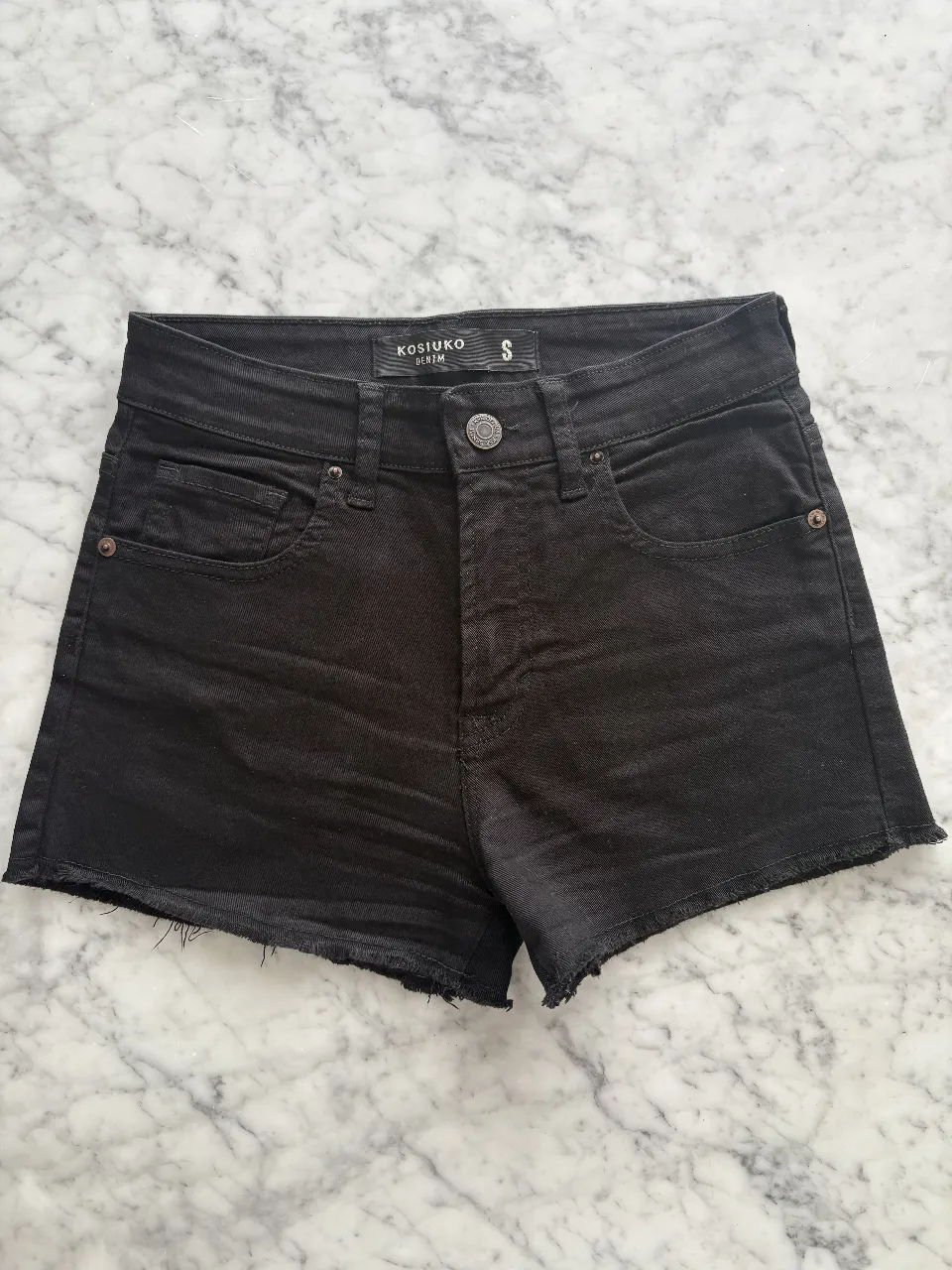 Shorts de jean negros tiro alto con roturas y detalles desflecados en el ruedo, elastizado. Un clásico para cualquier look.