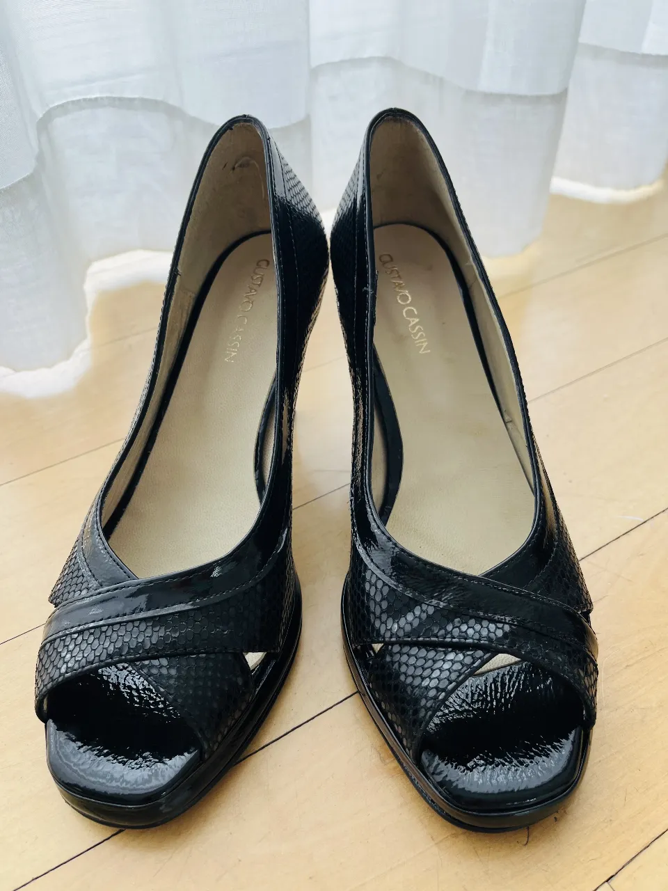 Zapatos de taco alto negros, estilo peep toe, con un diseño cruzado y textura de escamas. Ideales para un look elegante y sofisticado.