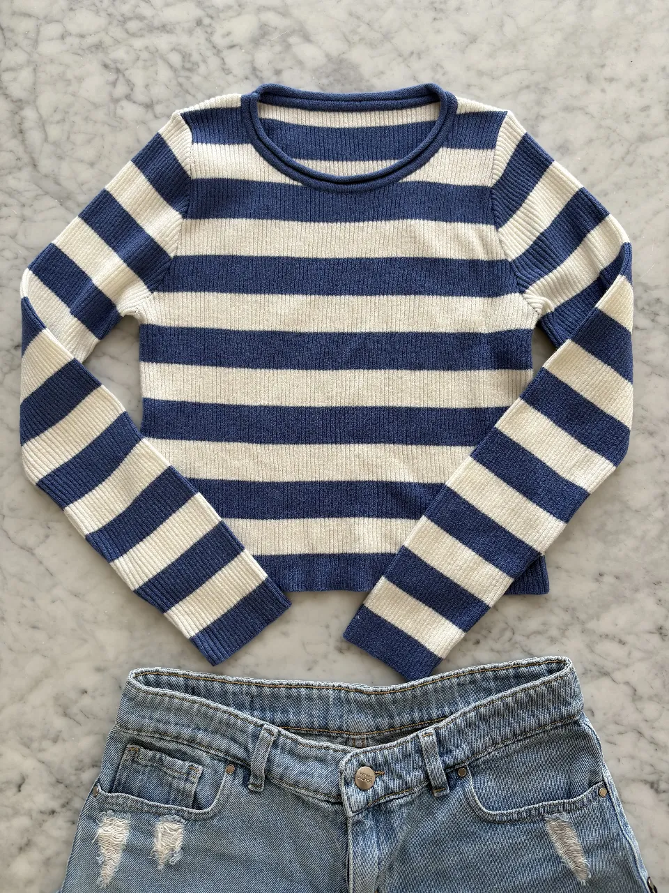Sweater de rayas azules y blancas, con mangas largas y cuello redondo. Ideal para un look casual y cómodo.