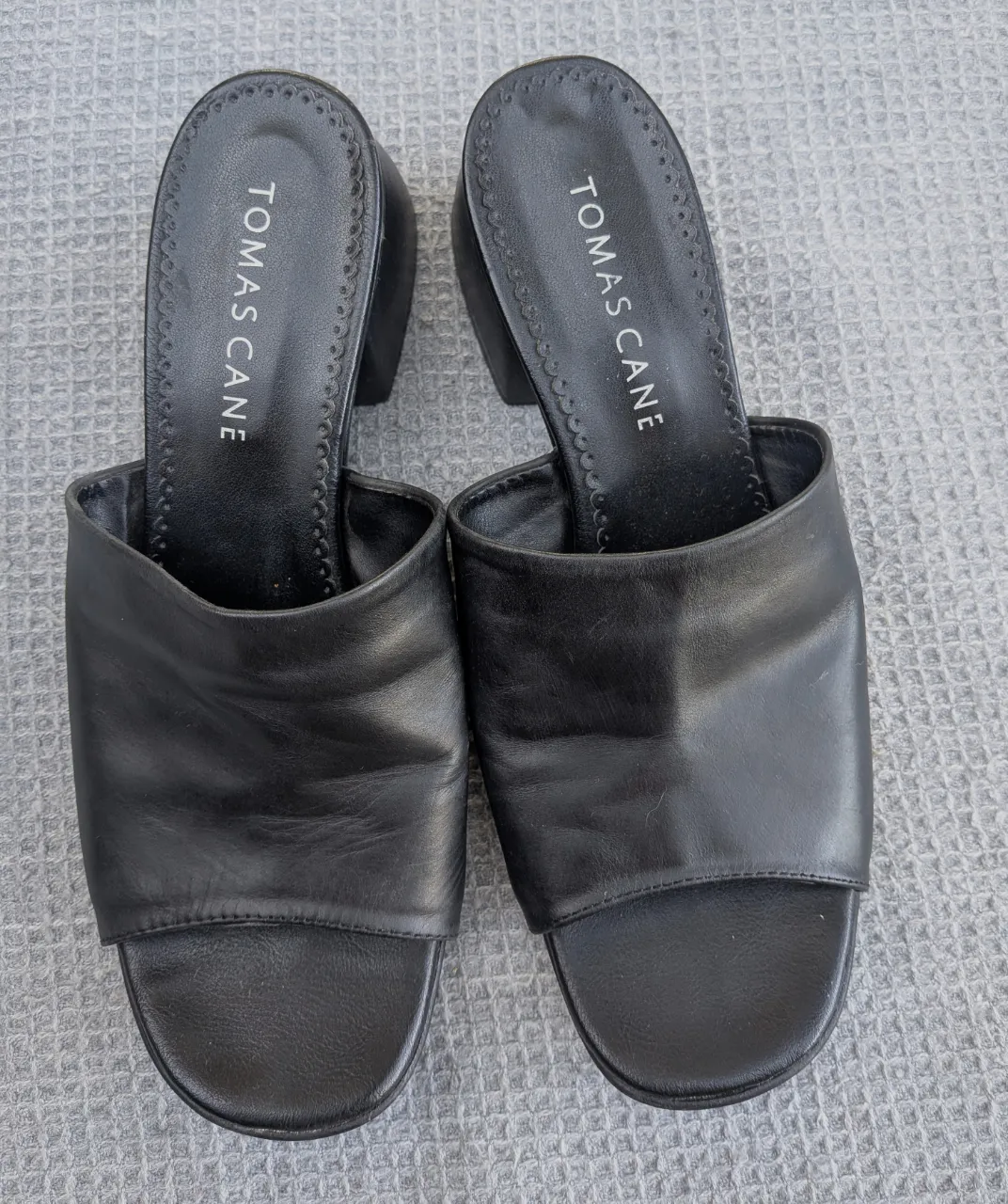 Sandalias negras de cuero con taco bajo y tiras anchas al frente. Marca 'TOMAS CANE' en la plantilla.